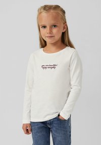 Valge pika varrukaga särk, millel on tikitud tekst "sa oled ilus, naudi iga päeva". Ühendatud siniste denimist teksadega, millel on lihtne sirge lõige.