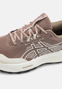 Brune atletisk sko med mesh-overdel, mønstrede snørebånd, hvit logo og såle, med AmpliFoam+ dempingsteknologi for støtte.
