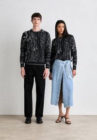 Zwart-wit gestreepte truien gecombineerd met zwarte broeken en een lichtblauwe denim wikkelrok. Model draagt strapless zwarte hakken.