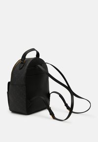 Sac à dos en cuir noir de forme arrondie, avec une fermeture éclair dorée, un motif texturé et des bretelles ajustables. Deux poches latérales incluses.