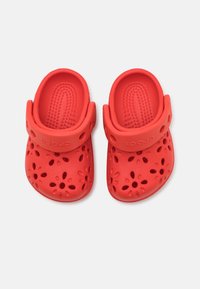 Punaiset muoviset puukengät, joissa on rei'itetyt kukkakuviot, muotoiltu pohjallinen ja säädettävä remmi. Valmistettu kevyestä, joustavasta materiaalista.