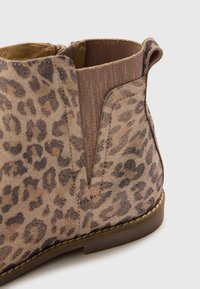 Botín de tobillo con estampado de leopardo, hecho de tejido texturizado con una paleta de colores en tonos marrones. Cuenta con paneles laterales elásticos y un diseño de punta redonda.