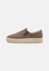 Zapato de ante marrón tipo slip-on con paneles laterales elásticos, suela de goma beige y silueta aerodinámica. Presenta detalles de costura mínimos.