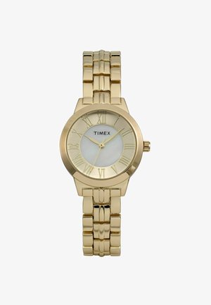 Montre en métal doré avec un cadran rond, des chiffres romains et un bracelet texturé. Elle présente un fond blanc et un logo centré au-dessus des marqueurs numériques.