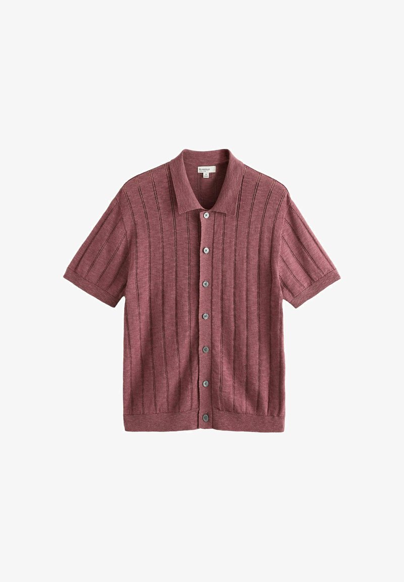 Chemise à manches courtes, boutonnée, couleur rose poudré avec une texture côtelée verticale et un col classique, présentée sur un fond blanc.