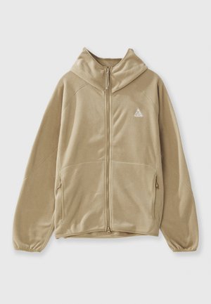 Veste en polaire beige avec capuche, dotée d'une fermeture éclair à l'avant, de deux poches latérales et d'un petit logo triangulaire blanc sur la poitrine. Texture douce.