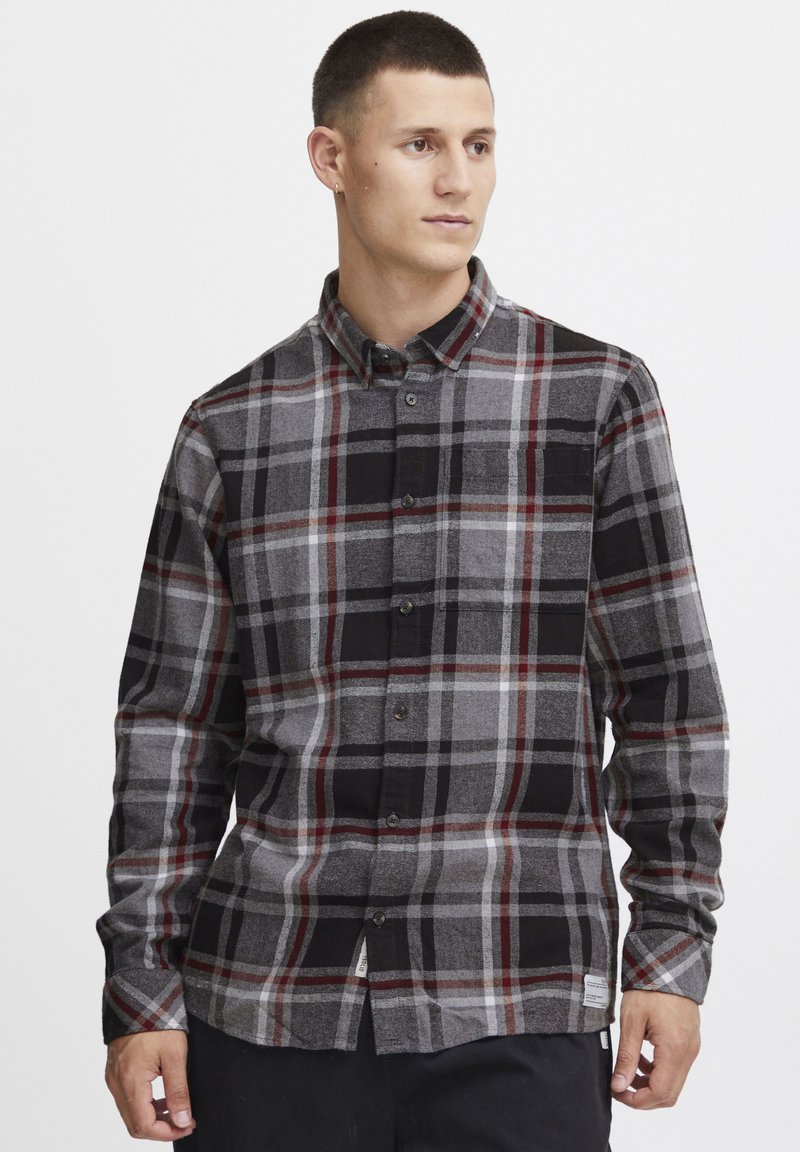 Graues und schwarzes kariertes Hemd mit roten Akzenten und einer Brusttasche. Weicher Stoff, lange Ärmel und abgerundeter Saum mit Etikettendetail.