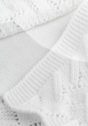 Fehér kötött takaró, texturált mintákkal, sima és bordázott részekkel, valamint finom csipkés díszítéssel, mindez egy puha, egyenletes kötésben.
