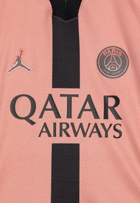 Maillot de football rose avec des rayures verticales noires, arborant un logo circulaire du Paris Saint-Germain et un logo noir de Jordan sur le côté gauche.