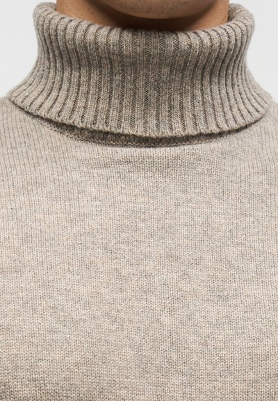 Μπεζ πουλόβερ με ζιβάγκο κατασκευασμένο από λεπτό πλεκτό ύφασμα με ριμπ γιακά, που παρουσιάζει απαλή υφή και εφαρμοστή σχεδίαση.