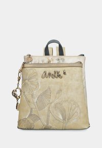 Zaino in finta pelle beige con ricami floreali, doppi manici superiori, spallacci regolabili e una tasca frontale con cerniera e charm decorativo.