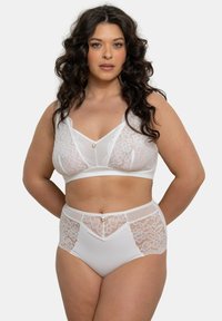 Bralette en dentelle blanche avec un décolleté en V, des bonnets doux et un petit anneau décoratif. Le bas assorti, en taille haute, présente des panneaux en dentelle et un détail de bouton discret.