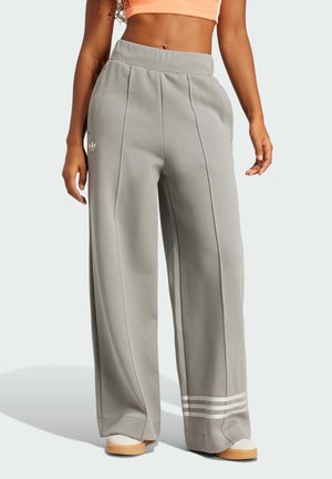 Wide-leg sweatpants in light gray fabric with pleats, featuring a white logo on the hip and three white stripes at the hem.