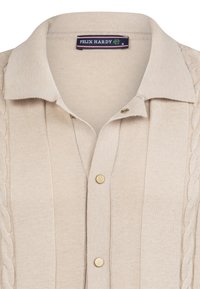 Beige gestricktes Polohemd mit gerippter Textur, flachem Kragen, drei goldenen Knöpfen und einem Kabelstrickmuster an den Seiten.