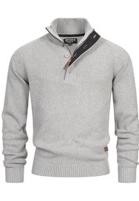 Suéter gris de punto con cuello half-zip, puños y dobladillo acanalados, y dos botones de contraste en la tapeta. Incluye una etiqueta de acento de cuero.