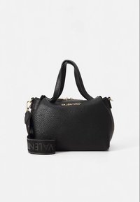 Crna kožna torba zrnaste teksture, s zlatnim okovima, gornjim ručkama i odvojivim remenom na kojem je ime brenda ispisano podebljanim slovima.
