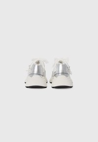 Hvide sneakers med metallisk sølvakcent, struktureret overdel, tyk sål og snørebånd. Bemærkelsesværdige detaljer inkluderer en bagloop og subtile designlinjer.