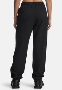 Black sweatpants with an elastic waistband and cuffed ankles, featuring a smooth, soft texture and a relaxed fit. No visible branding.