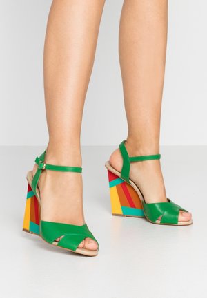 Sandales à talons en cuir vert avec un design à bout ouvert, dotées d'un talon bloc à motifs géométriques multicolores et d'une fine bride à la cheville.