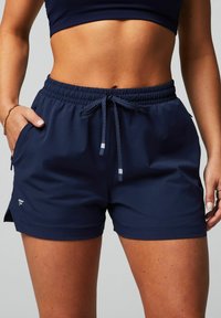 Marineblaue Sportshorts aus leichtem Fabric mit elastischem Bund, Kordelzug, seitlichen Taschen und einem kleinen Logo-Detail.
