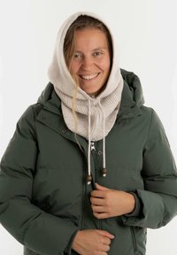 Donkergroene pufferjack met capuchon, voorzien van een lichtbeige geribde gebreide sjaal en koordjes met houten kralen, gedragen door een persoon.