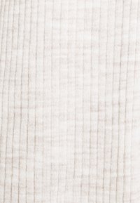 Gros plan d'un tissu tricoté côtelé beige clair avec des lignes verticales texturées et une apparence douce, légèrement chinée.