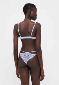 Light blue lace bralette and thong set with intricate floral patterns; adjustable straps; smooth fabric; delicate detailing on the back.