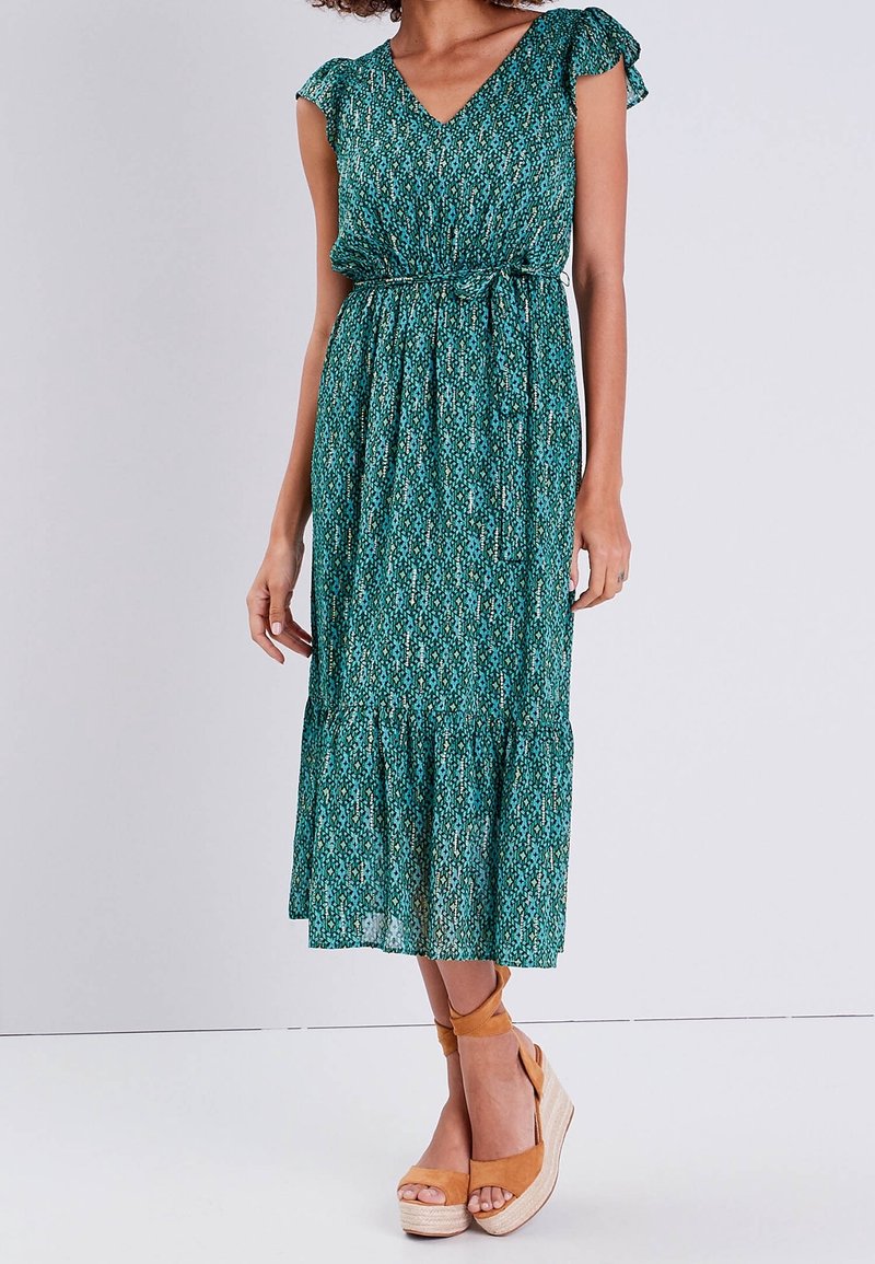 Robe midi à motifs floraux turquoise avec des manches courtes à volants, taille élastique et jupe à volants ; associée à des escarpins compensés en toile beige.