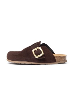 Zoccolo in suede marrone con punta larga e arrotondata, accentato da una fibbia in tono dorato. Suola in sughero e suola in gomma testurizzata per una buona aderenza.