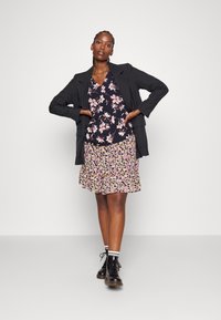 Black blazer over a floral blouse and a frilled skirt. Textured black boots with white striped socks. Various floral patterns in pink and beige.