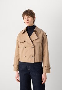 Beige lühike trench coat kahekordse eesmise nööbiga, suure kaelusega ja snap-nööbiga detailidega. Sile kangas ja mansettide rihmad rikastavad disaini.