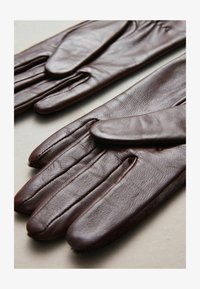 Guantes de cuero marrón con una textura suave, diseño ajustado y costuras detalladas a lo largo de las costuras. Estilo delgado y sin dedos.