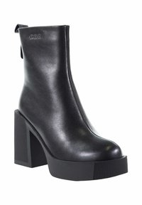Czarny skórzany botek za kostkę z grubą platformą i wysokim słupkowym obcasem. Posiada okrągły czubek oraz fakturowane, żebrowane detale na podeszwie.