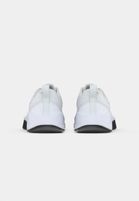 Hvit sportssko med nettingoverdel, polstret krage, flate snørebånd, løkke på hælen og sort gummisåle, med et minimalistisk design.