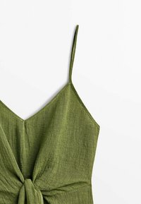 Robe verte sans manches avec fines bretelles et détail d'un nœud noué à l'avant sur fond blanc.