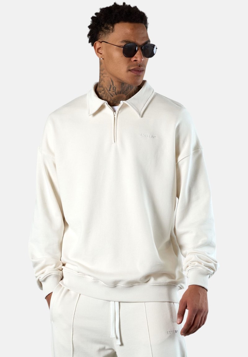 Cremefarbenes Sweatshirt aus weichem Stoff, mit einem Reißverschlusskragen, gerippten Bündchen und einem dezenten Logo auf der Brust.