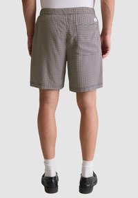 Heren geruite shorts in zwart en wit, gemaakt van lichte stof. Beschikt over een elastische tailleband en een achterzak.