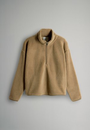 Beige fleece pullover with a stand collar, half-zip front, and long sleeves. Soft texture and relaxed fit.