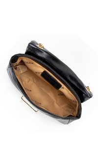 Sac à main en cuir noir au design structuré, avec des accessoires en or et un intérieur en satin. Il dispose d'un seul compartiment et d'une étiquette portant le nom "Wittchen."