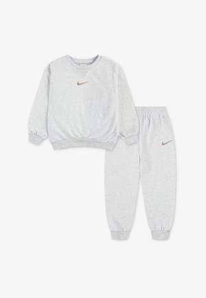 Halli dressipluus ja sobivad püksid, valmistatud pehmest kangast. Varustatud soonikkoes varrukaotste ja vöökohaga, mõlemal tükil väike pruun Nike logo.