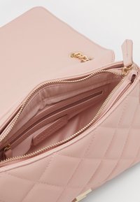 Quiltad rosa syntetisk handväska med detaljer i guldton, som har dragkedjestängning och flera innerfickor. Slät yta.