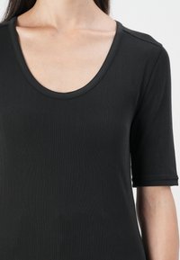 Zwarte geribbelde top met een ronde halslijn en korte mouwen, met een gladde textuur en een getailleerd ontwerp.