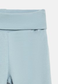 Colanți bleu deschis dintr-un material moale, texturat. Prezintă un talie lată, pliată și un design ajustat. Ideali pentru confort și ușurința mișcării.