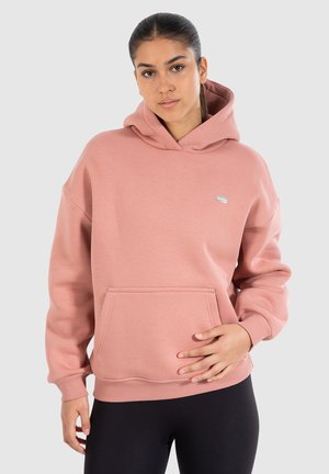Hoodie en polaire rose avec une grande poche et des poignets côtelés, arborant un petit logo sur le côté supérieur gauche. Conception douce et ample.