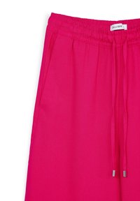 Rosa, leichte Hose mit elastischem Bund und Kordelzugverschluss. Hat eine glatte Textur und metallische Akzente an den Enden der Kordel.