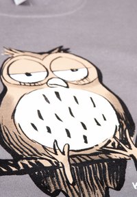 Maglietta in cotone grigia con un grande design di un gufo in stile fumetto con caratteristiche esagerate e dettagli neri, su uno sfondo più chiaro.