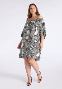 Vestido sin mangas en crema con estampado de hojas de palma negras, que presenta un corte holgado, mangas cortas y un dobladillo ligeramente acampanado.
