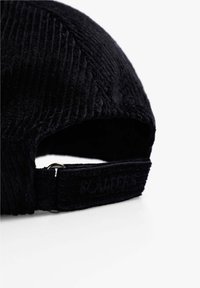 Gorra de pana negra con tejido texturizado, visera curvada y correa ajustable que presenta un branding en relieve. Diseño sencillo con construcción duradera.