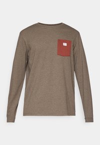 Camisa de manga larga de algodón marrón oscuro con un bolsillo rojo en el lado izquierdo del pecho, que presenta una pequeña etiqueta de logo por encima del bolsillo.