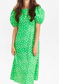 Zielona sukienka z bufkami, z dopasowanym gorsetem i długą spódnicą. Udekorowana dużymi białymi kropkami na gładkim materiale.